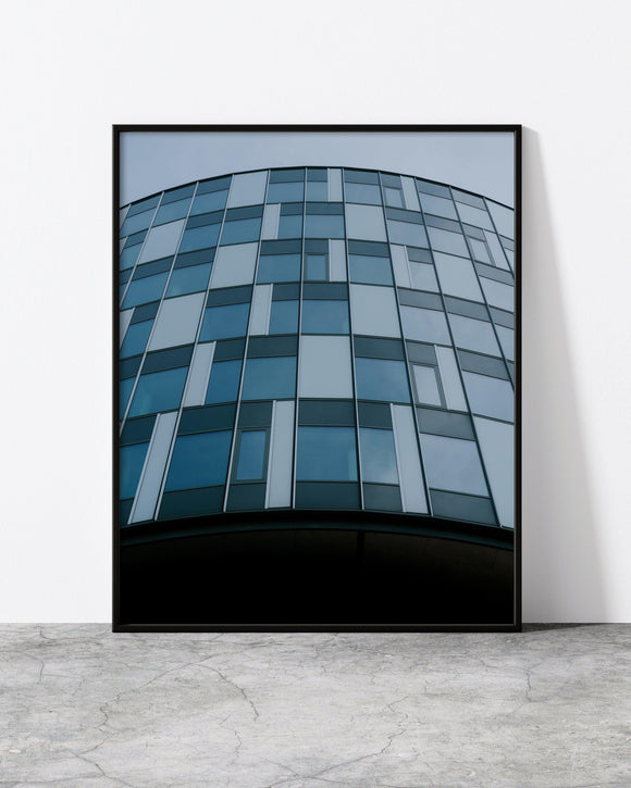 Modern urban wall art showcasing a cylindrical building with reflective blue-tinted windows.