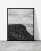 Black and white mountain landscape print featuring two hikers standing on a rugged cliff edge with vast scenery.