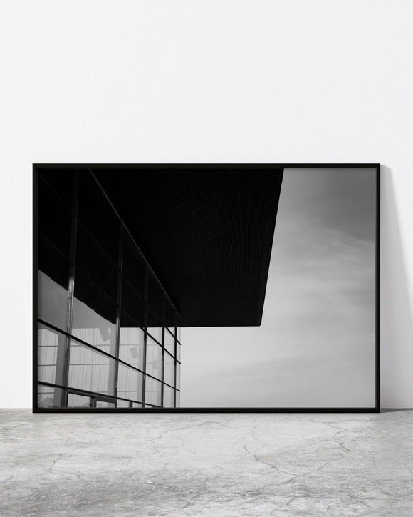Minimalist black and white architectural photograph featuring a sharp overhanging roof and glass facade.