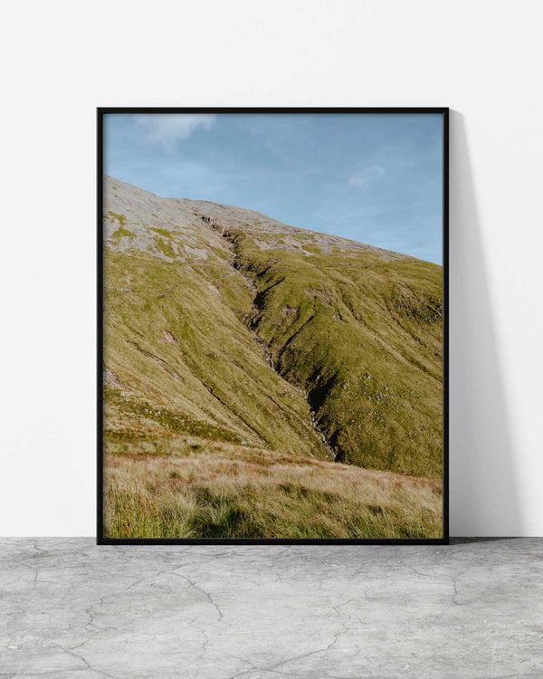 Minimalist landscape print featuring a serene mountain slope covered in lush green grass under a clear sky.