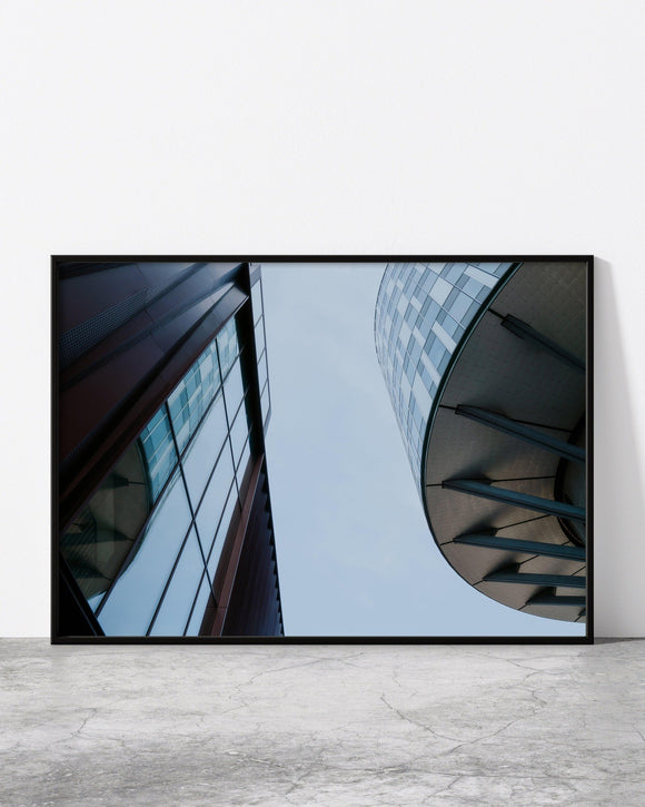 Minimalist architectural print featuring an upward view of two modern buildings with curved and angular designs.