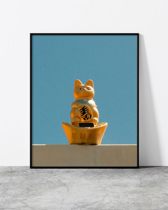 Cat wall art of a golden lucky cat figurine against a clear blue sky