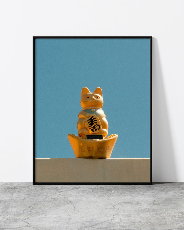 Cat wall art of a golden lucky cat figurine against a clear blue sky