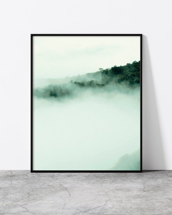 Foggy landscape print of morning sun breaking through mist over a wooden fence on a green Madeira hillside