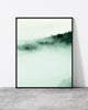 Foggy landscape print of morning sun breaking through mist over a wooden fence on a green Madeira hillside