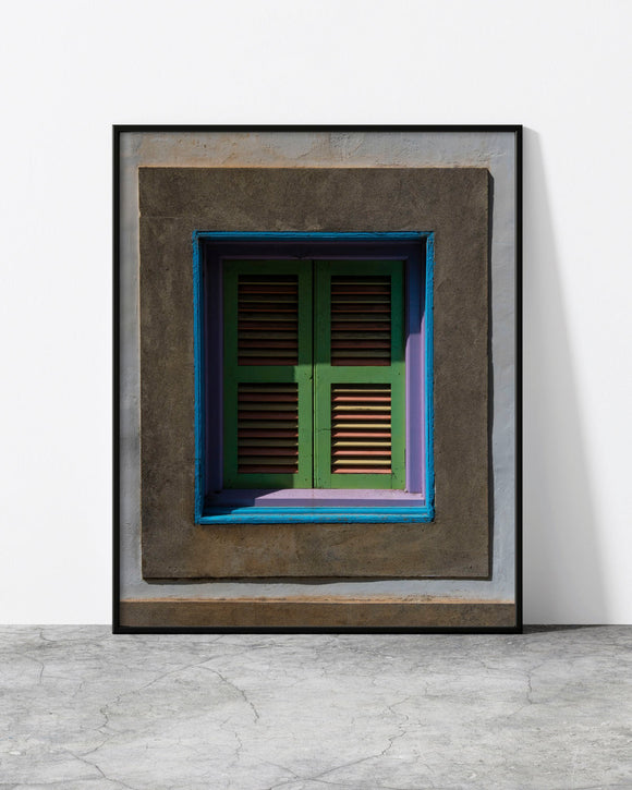 Colourful window print of weathered green, lilac and blue shutters framed by grey plaster