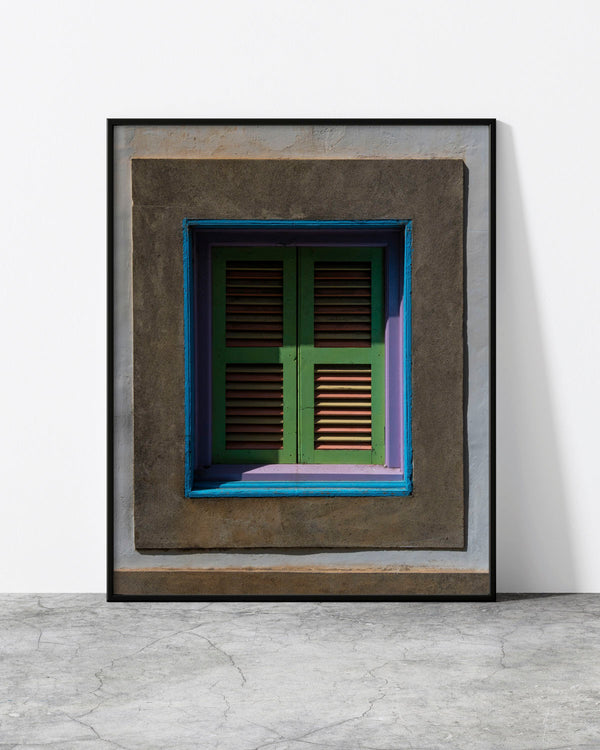 Colourful window print of weathered green, lilac and blue shutters framed by grey plaster