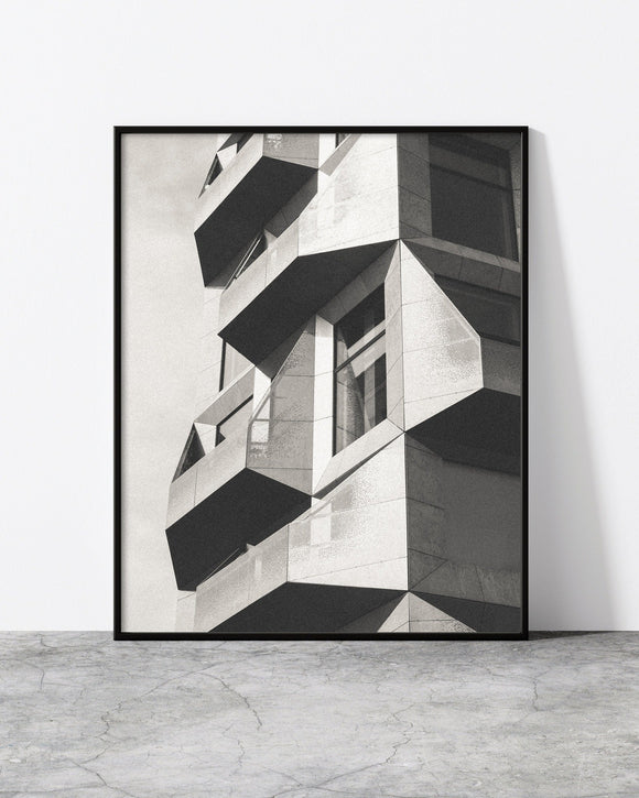 Black and white architectural print showcasing a geometric modern facade with sharp angles and bold contrasts.