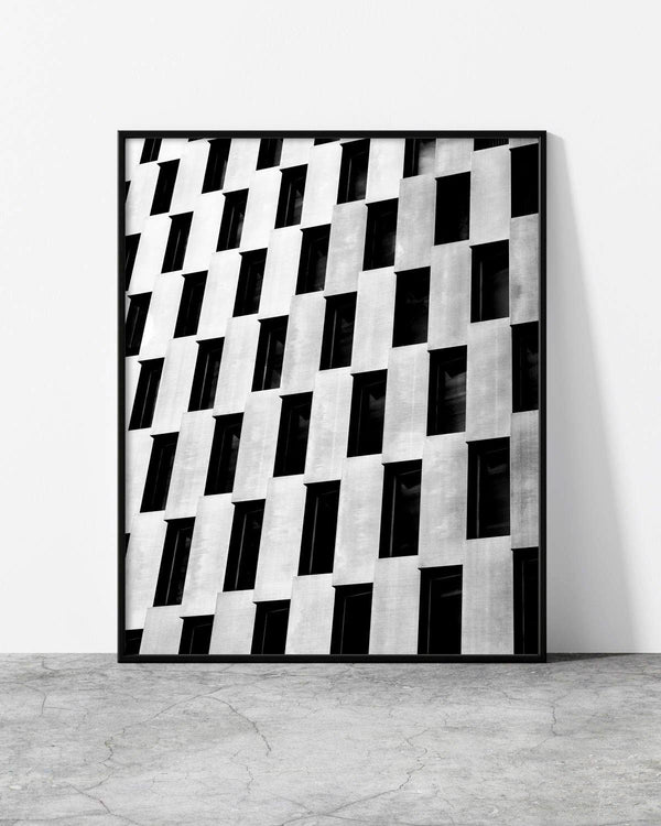 Black and white architectural photograph featuring a modern building facade with a rhythmic pattern of staggered windows.