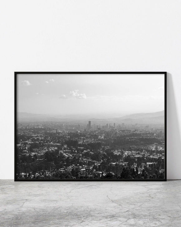 Minimalist urban photography featuring a hazy view of Addis Ababa, Ethiopia, blending city buildings with rolling hills under a soft sky.