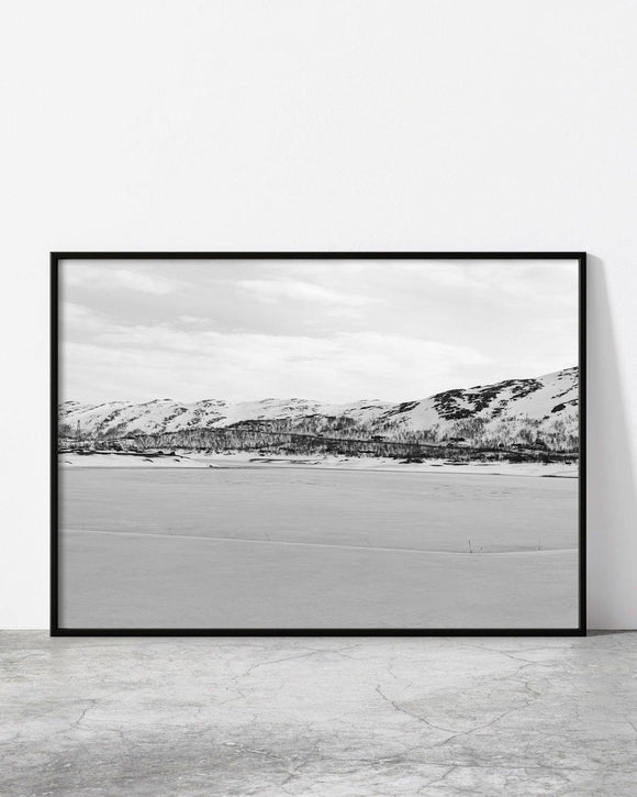 Minimalist black and white framed print of a snow-covered mountain landscape under a cloudy sky.