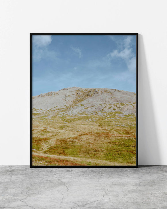Minimalist landscape print showcasing a rugged mountain peak under a clear blue sky with earthy tones.