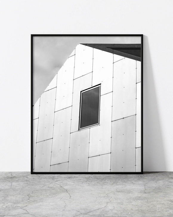 Minimalist black and white architectural photograph featuring a modern angular building facade with a single window.